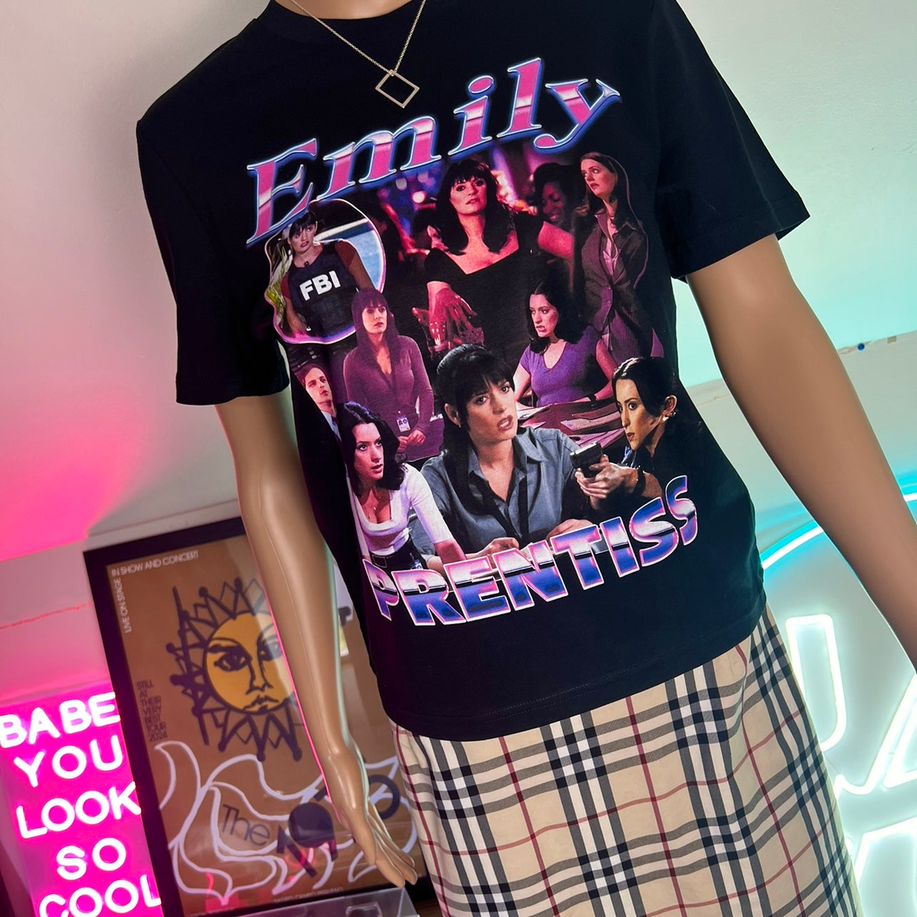 A black t-shirt featuring a colorful graphic print of a character named Emily Prentiss with various images and text related to the Criminal Minds series.